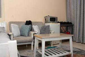 a living room with a couch and a table and a tv at Delore suits in Ongata Rongai 