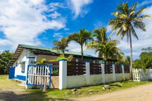 a house with a fence and palm trees at Hostal Rudy's Beach in Puerto Cortés +9 photos