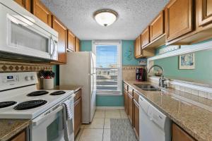 a kitchen with white appliances and wooden cabinets at Spacious 2BR Condo with Pool Across from the Beach in Gulf Shores