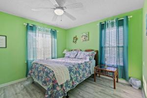a bedroom with green walls and a bed and a fan at Spacious 2BR Condo with Pool Across from the Beach in Gulf Shores