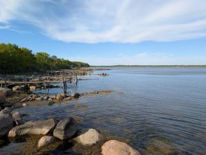 a large body of water with rocks and a dock at Kuggeboda in Listerby
