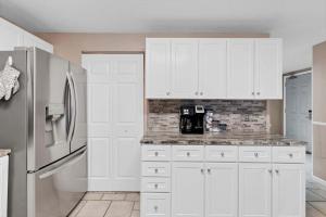 a kitchen with white cabinets and a refrigerator at 3BR 4BA Ground Floor Gulf Getaway in Gulf Shores +33 photos