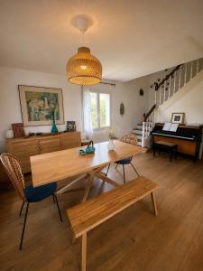 a living room with a wooden table and a piano at Chez Billie et Moon in Landéda