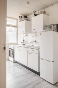 a white kitchen with white cabinets and a refrigerator at The Hague appartment in The Hague +20 photos