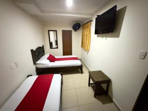 a room with two beds and a flat screen tv at Hotel Tucan Pereira in Pereira