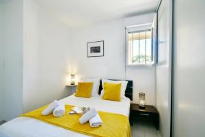 a bedroom with a bed with yellow pillows and a window at Mer et plage Standing Presta in Cannes