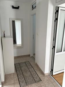 a hallway with white walls and a door and a rug at Apartmani Daria in Ljubuški