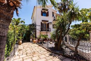 a house with palm trees in front of a fence at Villa Domina by Letstay in Giardini Naxos +29 photos