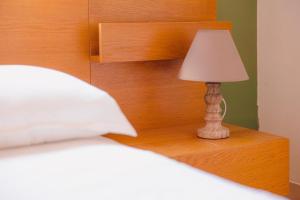 a lamp sitting on a night stand next to a bed at Zoumperi Summer House in Nea Makri +17 photos