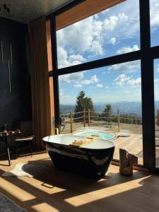 a bath tub sitting in a room with a large window at Ascent Lodge -Jacuzzi si Panoramic View in Petreasa