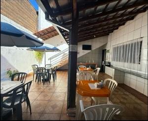 a patio with tables and chairs and an umbrella at Pousada Anhanguera in Ribeirão Preto