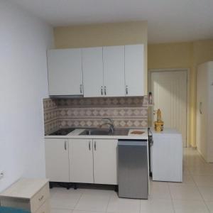 a kitchen with white cabinets and a sink at Private Rooms in Velipojë