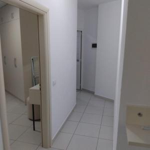 an empty room with a white floor and a hallway at Private Rooms in Velipojë