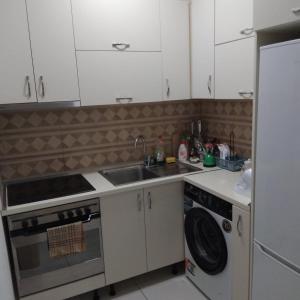 a kitchen with white cabinets and a sink and a dishwasher at Private Rooms in Velipojë +6 photos