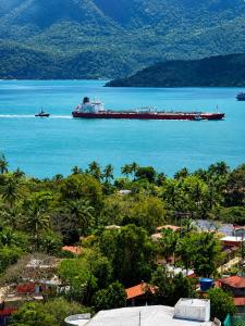 a large container ship in the water near a city at Studio Shogun Vista, Ar, Vaga 5 min do mar in Ilhabela