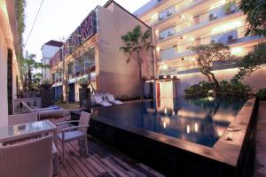 a hotel with a swimming pool in front of a building at Transera Kamini Legian Hotel in Legian