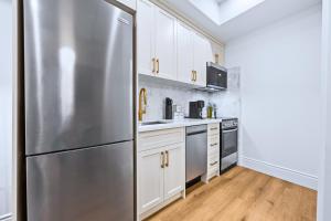 a stainless steel refrigerator in a kitchen with white cabinets at Casa Hotels Gerrard Private Basement Suite in Toronto