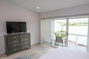 a bedroom with a tv and a dresser with a sliding glass door at 232D South Finger in Jolly Harbour