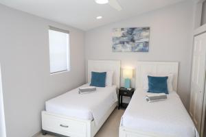 two beds in a white room with blue pillows at 232D South Finger in Jolly Harbour
