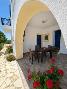 a patio with a table and red flowers at Green Parrot Apartments in Frátsia +49 photos