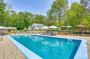 a swimming pool at a resort with tables and umbrellas at Community Perks: Monticello Cabin w/ Grill! in Mongaup Valley