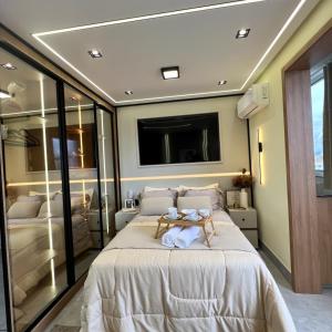 ein Schlafzimmer mit einem großen Bett und einem Fernseher an der Wand in der Unterkunft Royale Studio in Criciúma