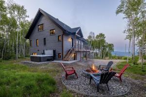 a house with a fire pit in front of it at Käbane Nova - La Chaleureuse in Baie-Saint-Paul