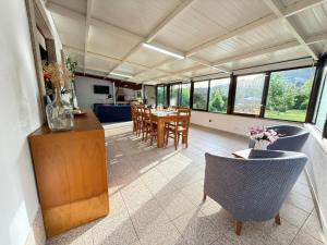 a living room with a table and chairs and windows at Casa Terra Nova - Gerês in Terras de Bouro