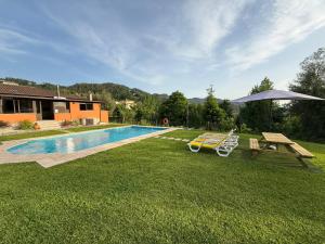 a pool with two lounge chairs and a picnic table at Casa Terra Nova - Gerês in Terras de Bouro