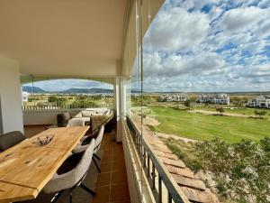 a large balcony with a wooden table and chairs at Beautiful apartment with golf and mountains view in Sucina
