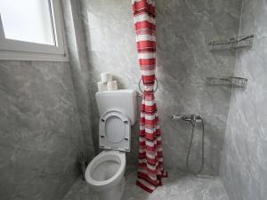 a bathroom with a toilet with a red and white shower curtain at Karma Seaside Apartment in Perea