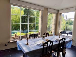 a dining room with a table and chairs and large windows at Domaine de la Brême in Bréménil