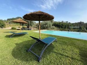 two chairs and an umbrella next to a swimming pool at Quinta do Paço - Casa do Caseiro in Vila Verde
