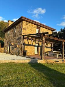 a large stone building with a wooden deck at A casiña do Rieiro in San Pelayo