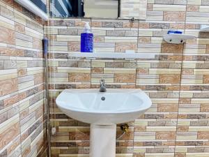 a white sink in a bathroom with wooden tiles at Appartement meublé service in Cotonou