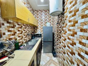 a kitchen with a refrigerator and a brick wall at Appartement meublé service in Cotonou