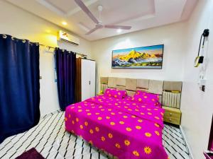 a bedroom with a pink bed with purple pillows at Appartement meublé service in Cotonou