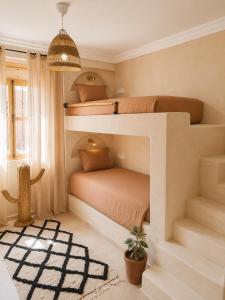 a bedroom with two bunk beds and a potted plant at Sines Surfmaroc in Tamraght Ouzdar