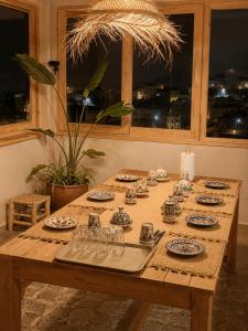 a wooden table with plates and glasses on it at Sines Surfmaroc in Tamraght Ouzdar +23 photos