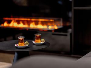 two cups of tea on a tray in front of a fireplace at Pullman Riga Old Town - Renovated 2025 in Riga
