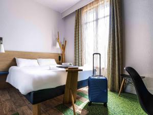 a hotel room with a bed and a suitcase at ibis Styles Moulins Centre in Moulins