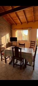 a dining room with a table and chairs and a piano at Cabañas del bosque in Merlo