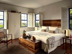 a bedroom with a bed with a wooden headboard and windows at Santa Teresa Hotel Rio de Janeiro - MGallery Collection in Rio de Janeiro