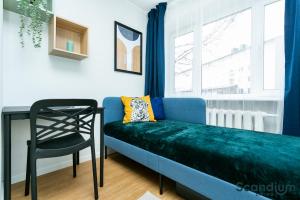 a blue couch in a room with a chair and a window at Sõle Studios by RevalHome in Tallinn