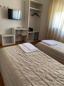 a hotel room with two beds and a desk and a television at AMLÈ in Papozze