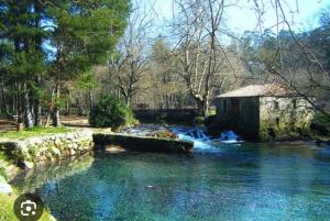 a river with a small building in the middle at O Ático in Rosal
