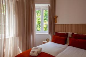 a bedroom with a bed with red pillows and a window at Santos da Vila in Sintra