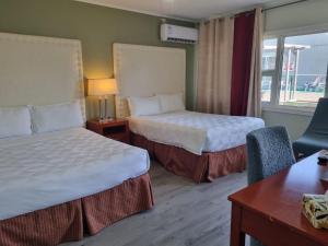 a hotel room with two beds and a desk at Manor Motel in Southampton