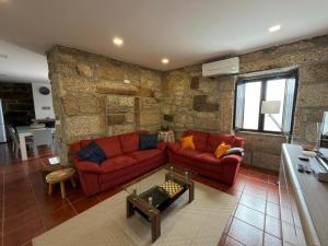 a living room with red couches and a stone wall at Casa Curto in Terras de Bouro