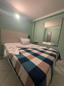 a bedroom with a bed with a checked blanket and a mirror at Hotel Romanza in Bogotá